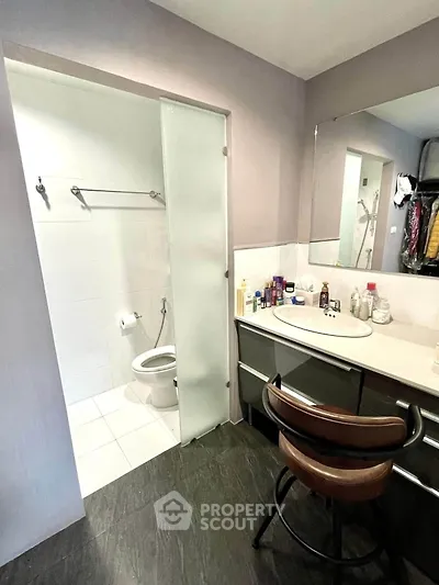 Modern bathroom with sleek design, featuring a large mirror and stylish chair, perfect for contemporary living.