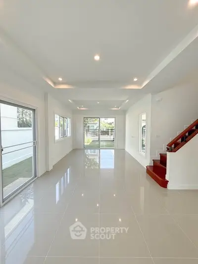 Spacious modern living room with glossy tile flooring and large windows for natural light.