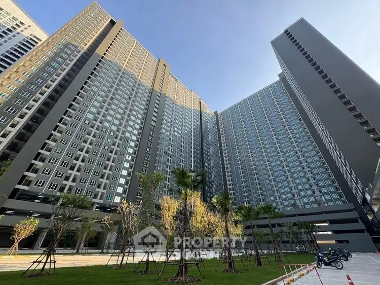 Stunning modern high-rise apartment building with lush landscaped gardens and clear blue sky.