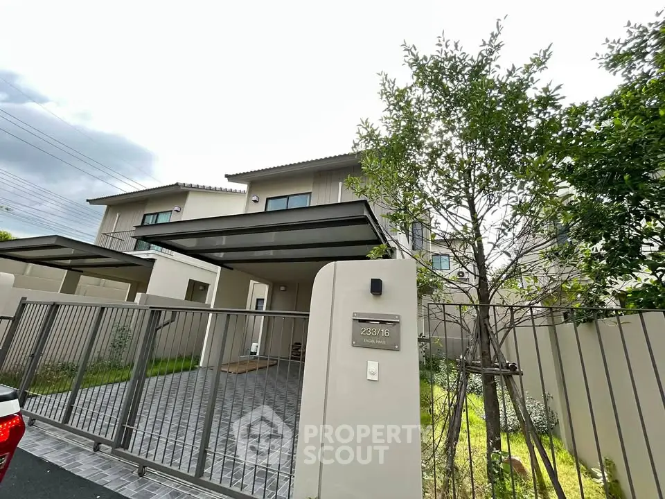 Modern two-story house with gated driveway and lush greenery