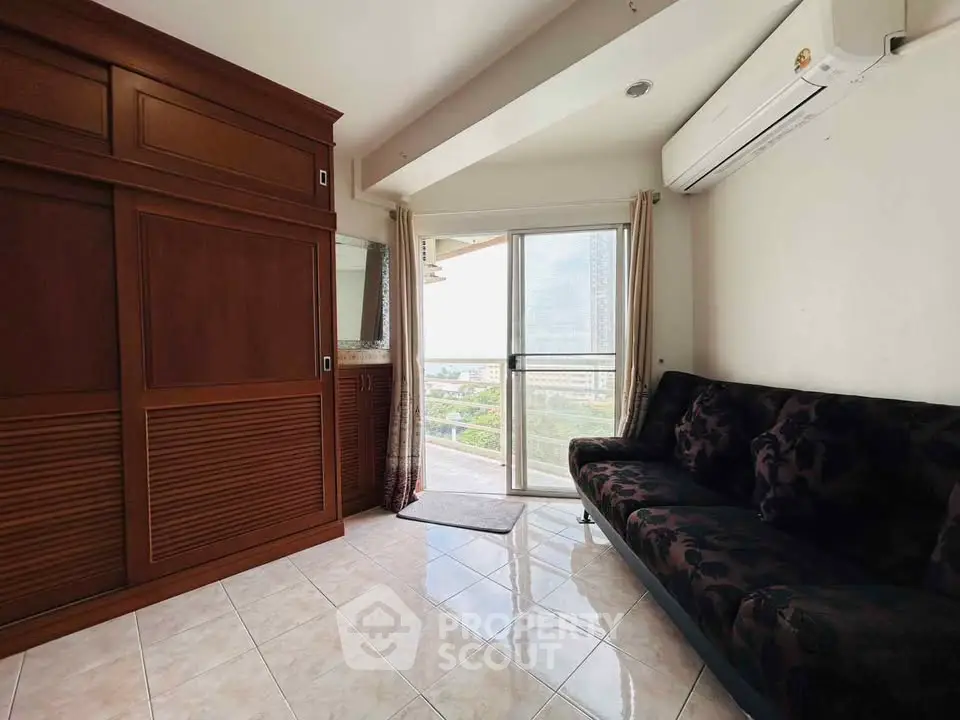 Cozy living room with elegant wooden cabinetry and plush sofa, featuring a balcony with a scenic view.