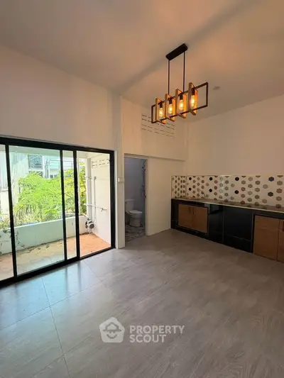 Spacious modern kitchen with open layout and stylish lighting, featuring large sliding doors to a balcony.