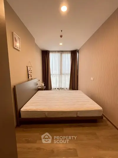 Spacious bedroom with large window and modern decor in a cozy apartment.