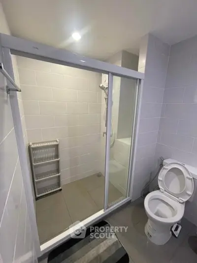 Modern bathroom with glass shower enclosure and sleek white tiles