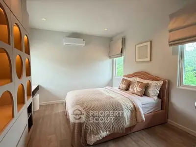 Cozy bedroom with elegant decor and large windows offering natural light.