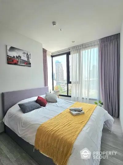 Modern bedroom with large windows and city view, featuring stylish decor and cozy ambiance.