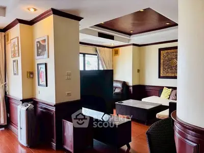 Spacious living room with elegant decor and natural light, featuring a cozy seating area and stylish wall art.