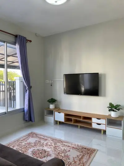 Modern living room with wall-mounted TV, stylish furniture, and large window for natural light.