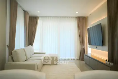 Elegant living room with modern decor, large TV, and cozy sectional sofa, perfect for relaxation.