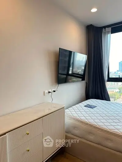 Modern bedroom with wall-mounted TV and city view, featuring sleek furniture and large window.