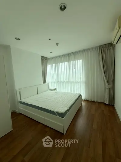Spacious bedroom with large windows and wooden flooring in modern apartment