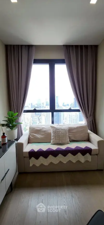 Cozy living room with city view, featuring a comfortable sofa and elegant curtains.