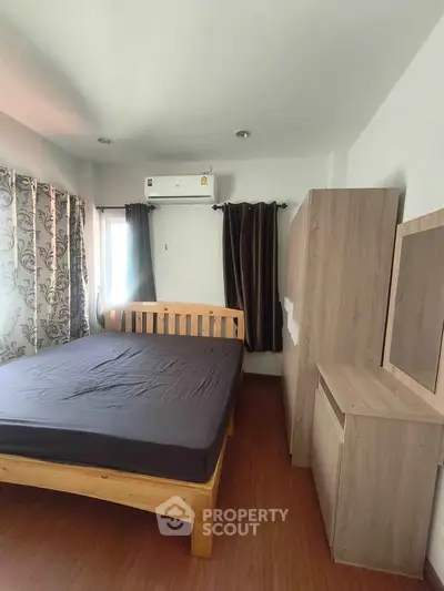Cozy bedroom with wooden furniture and air conditioning, perfect for relaxation.