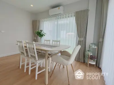 Elegant dining area with wooden flooring and modern furniture in a bright, airy room.