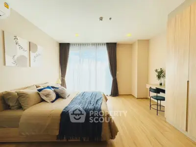 Spacious bedroom with modern decor and large window offering natural light.