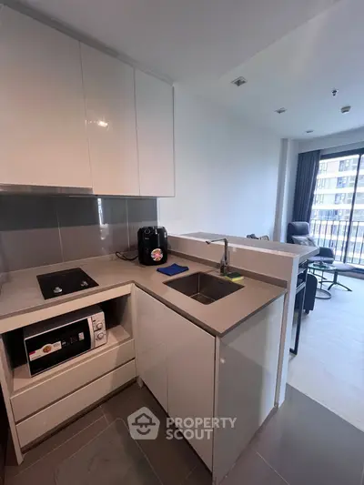 Modern compact kitchen with sleek cabinets and integrated appliances in a stylish apartment.