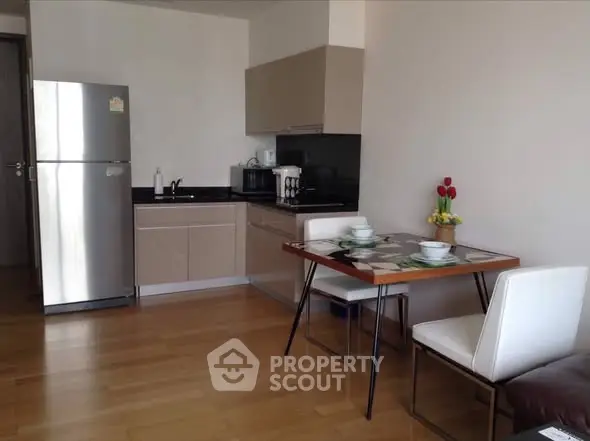 Modern kitchen with dining area, featuring sleek cabinetry and stainless steel appliances.