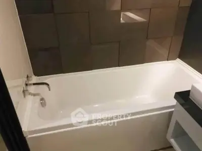 Modern bathroom with sleek bathtub and stylish tile wall design.