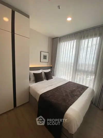 Modern bedroom with large windows and stylish decor in a high-rise apartment.