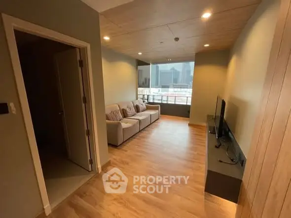 Modern living room with city view, wooden flooring, and cozy seating area.