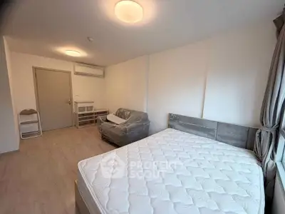 Spacious bedroom with modern furnishings and natural light, featuring a comfortable bed and cozy seating area.
