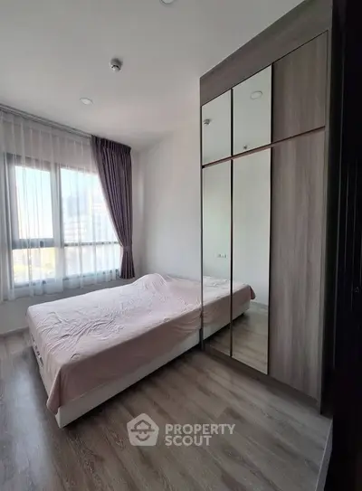Modern bedroom with large window and mirrored wardrobe in a stylish apartment.
