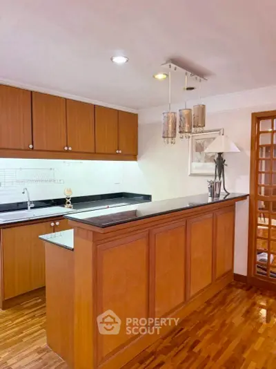 Elegant kitchen with wooden cabinets and modern lighting in a cozy apartment.