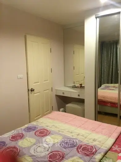 Cozy bedroom with mirrored wardrobe and floral bedding in modern apartment