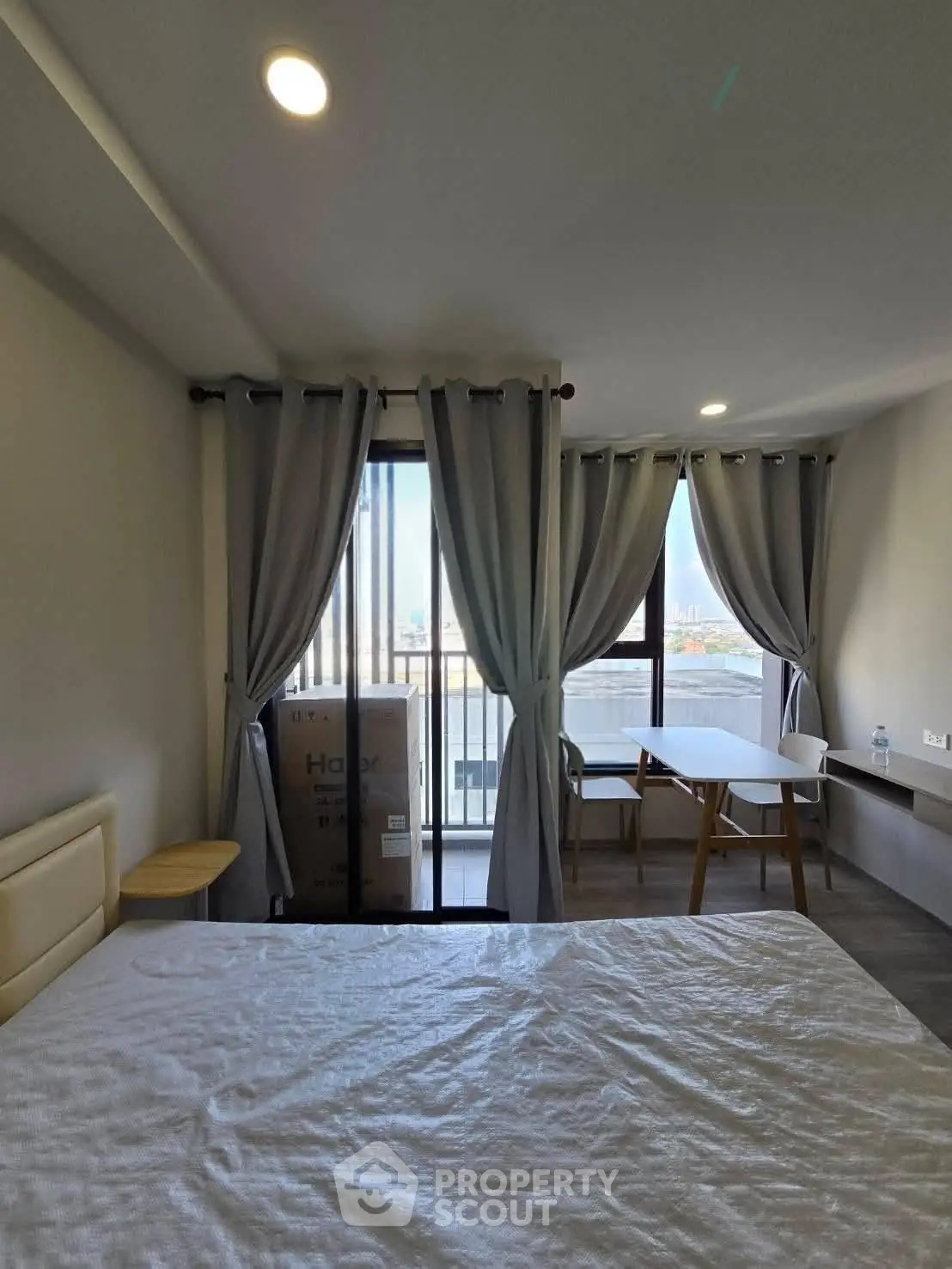 Modern bedroom with balcony view, featuring elegant curtains and stylish furniture, perfect for urban living.