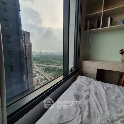Cozy bedroom with stunning city view from large window, perfect for relaxation.