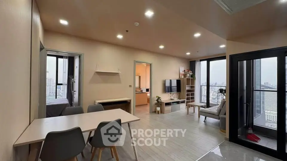 Modern open-plan living room with city view balcony, stylish furniture, and dining area.