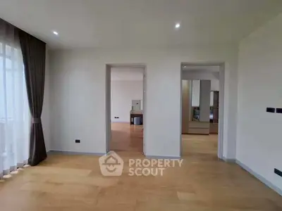 Spacious modern living room with wooden flooring and large windows for natural light.