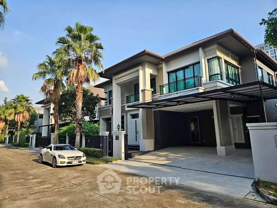Luxurious modern house with spacious driveway and palm trees in a serene neighborhood.
