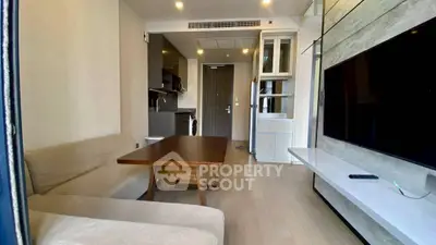 Modern living room with sleek furniture and open kitchen layout in a stylish apartment.