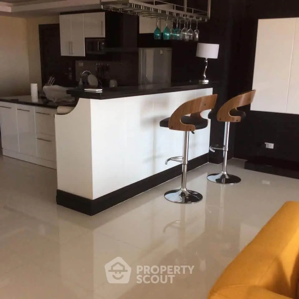 Modern kitchen with sleek bar stools and glossy flooring in a stylish apartment.