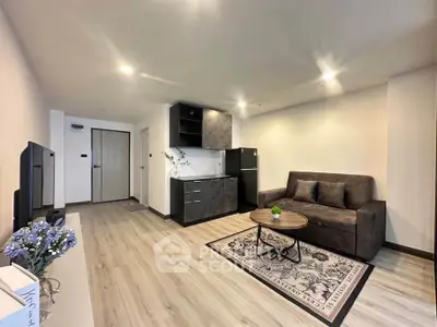 Modern living room with sleek kitchen and cozy seating area in open layout apartment.