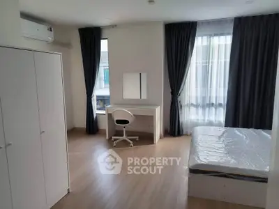 Spacious bedroom with modern furnishings and large windows for natural light.