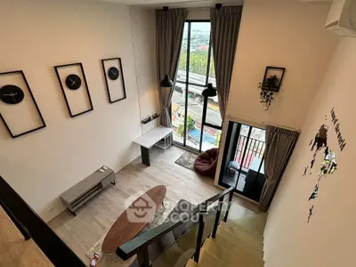 Modern loft-style living room with high ceilings and large windows offering stunning city views.