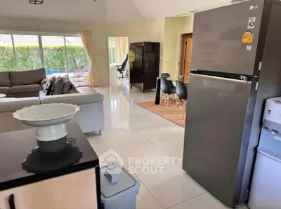 Spacious open-plan living room with modern kitchen and dining area, featuring large windows and stylish furniture.