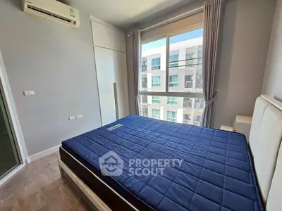 Modern bedroom with large window and blue bedding in a high-rise apartment.