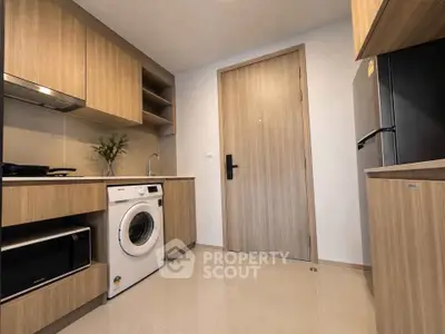 Modern kitchen with wooden cabinets, washing machine, and sleek appliances in a compact layout.