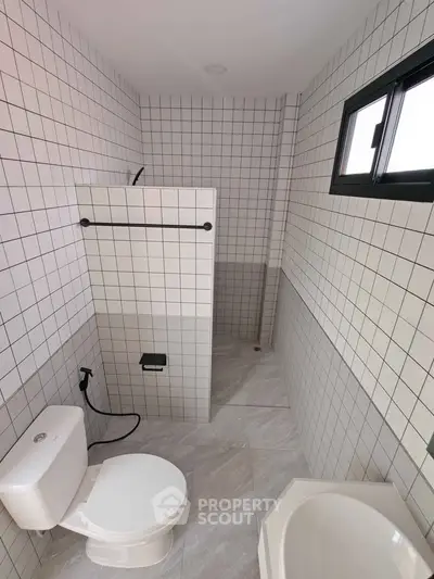 Modern tiled bathroom with shower and toilet in minimalist design.