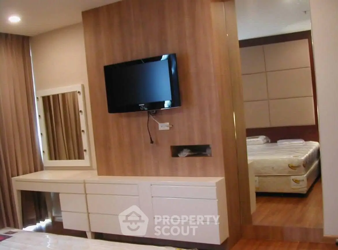 Modern bedroom with wall-mounted TV and stylish vanity in elegant apartment.