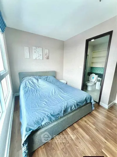 Modern bedroom with ensuite bathroom and large window, featuring stylish decor and wooden flooring.