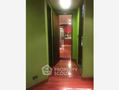 Charming hallway leading to a vibrant kitchen with red cabinets and modern appliances.