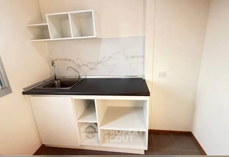 Modern kitchen with sleek cabinetry and marble backsplash in a compact layout.
