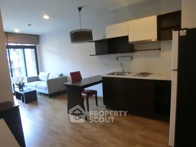 Modern open-plan living room with kitchen and dining area, featuring sleek furniture and wooden flooring.