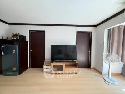 Modern living room with TV, fan, and sleek wooden flooring