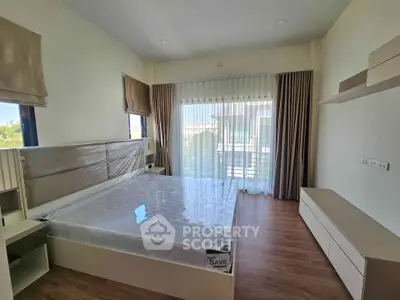 Spacious bedroom with large windows and modern furnishings in a bright, airy setting.