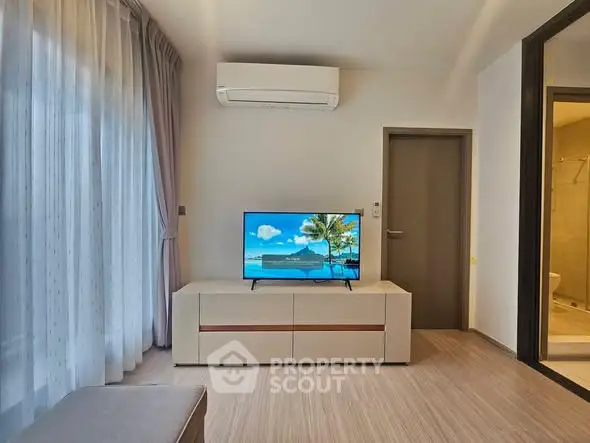 Modern living room with air conditioning and flat-screen TV, featuring elegant curtains and wooden flooring.